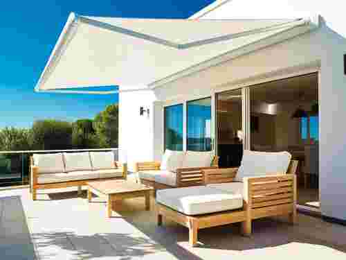 Ausgefahrene Markise über einer Terrasse mit Holzlounge, montiert von Sonnenschutztechnik Lohmar.