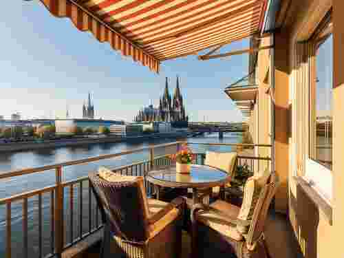 Balkon mit gestreifter Markise und Blick auf Rhein und Kölner Dom, Markise Köln von Sonnenschutztechnik Lohmar.