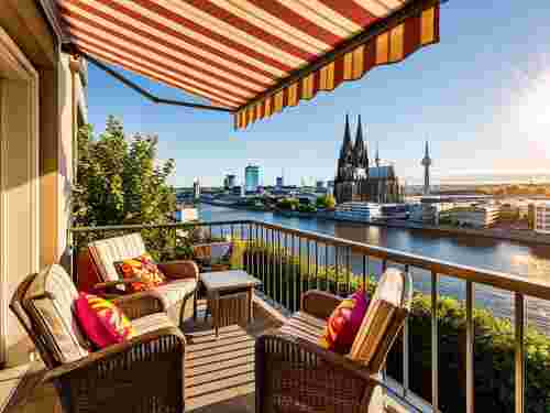Balkon in Köln mit rot-gelb gestreifter Markise bei Sonnenschein, Sonnenschutztechnik Lohmar.